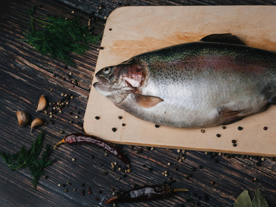 木桌子上的木板上的新鲜鳟鱼, 用于烹饪。生红鱼