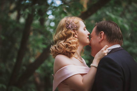 新娘和新郎在夏天的森林里接吻。