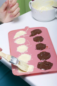 一个女人用刷子刷一个融化的巧克力硅胶模具作为甜点。