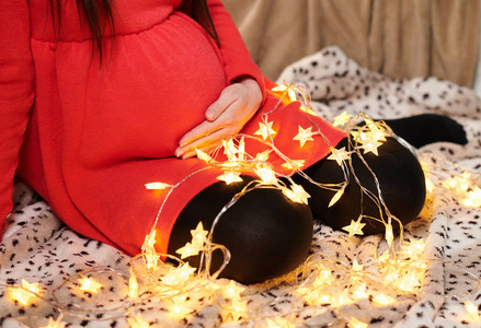 孕妇摆姿势圣诞灯红色礼服节日概念