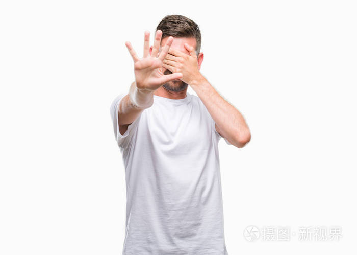 年轻的帅哥在孤立的背景上用手遮住眼睛,用悲伤和恐惧的表情做停止的
