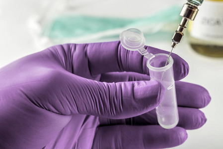 戴绿色乳胶手套的科学家在实验室概念图像中操纵小瓶和注射器