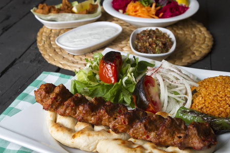 近距离观看土耳其和阿拉伯传统的阿达纳烤肉串，盘子里有沙拉