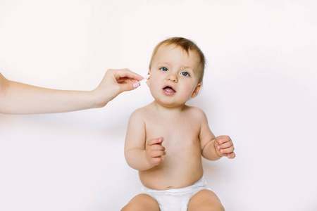 特写肖像宝宝。母亲用棉签清洁婴儿耳朵，隔离在白色背景上。新生儿卫生。概念清洗擦拭，纯，干净。
