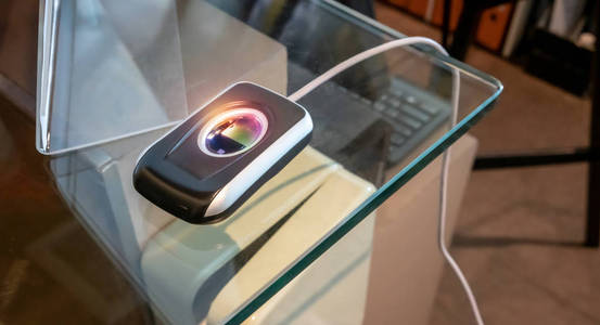 玻璃桌上的指纹扫描仪，用于检查安全系统。 指纹和密码锁在办公楼，指纹扫描仪控制机，用于记录工作时间，解锁门办公室。