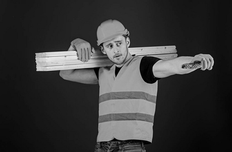 木匠, 木工, 强的建设者在繁忙的面孔运载木横梁在肩膀上。木质材料的概念。男子头盔, 硬帽子和防护手套指向方向, 蓝色背景