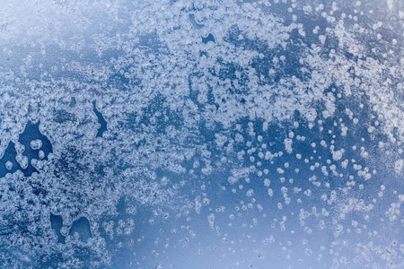 冬天雪花和霜的蓝色背景。 窗户上的冬天图案