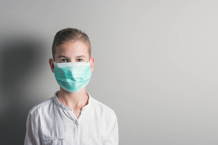 小男孩，一个戴着医疗面具的孩子，背景明亮。 流行性流感保护免受疾病疫苗接种的想法。