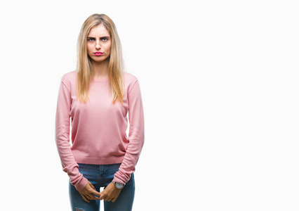 年轻漂亮的金发女人穿着粉红色的冬季毛衣，在孤立的背景下沮丧和担心痛苦，哭泣，愤怒和害怕。 悲伤的表情。