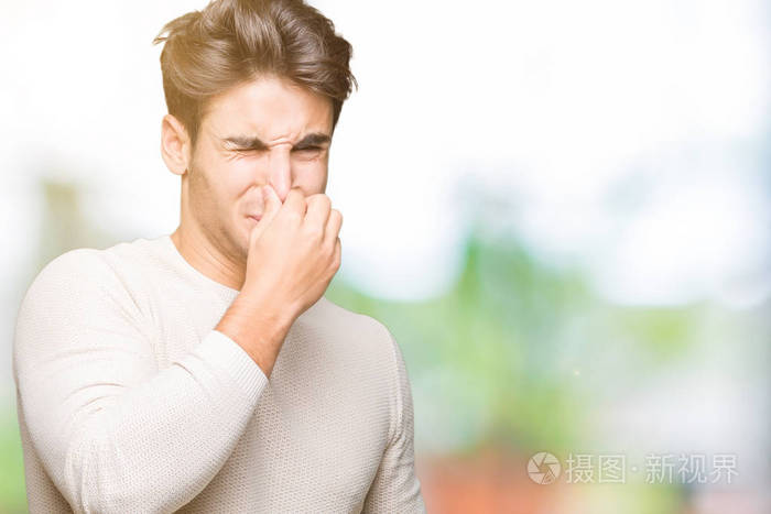 年轻的帅哥在孤立的背景上闻到了一些臭味和令人恶心的难以忍受的气味