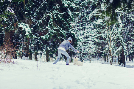 一个年轻的女人和她的狗在下雪的冬天玩耍