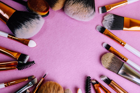 从一套美丽的不同的软化妆刷从自然皮棉的框架, 以瞄准美丽, 并在一个立场和复制空间在粉红色, 紫色的背景