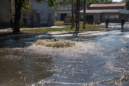 水从道路污水舱口流出。 污水的排水喷泉。 污水系统事故。 肮脏的污水在道路上流动喷泉。 从舱口流出的水