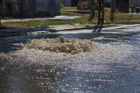 水从道路污水舱口流出。 污水的排水喷泉。 污水系统事故。 肮脏的污水在道路上流动喷泉。 从舱口流出的水