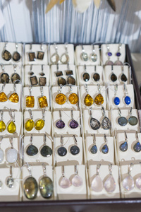 珠宝套耳环与不同颜色的石头。 在商店里用石头设置耳环。 垂直照片