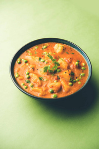 印度芦荟咕哝咖喱土豆和豌豆浸泡在洋葱番茄肉汁中，用香菜叶装饰。 在卡拉希卡德海或平底锅或碗中供应。 选择性聚焦