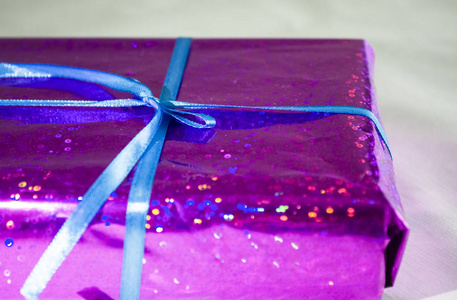 在紫罗兰色和有光泽的包装与蓝色丝带与弓的礼物