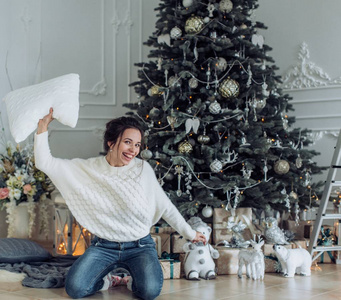 美丽的女人在家门口的圣诞树旁摆姿势玩得开心