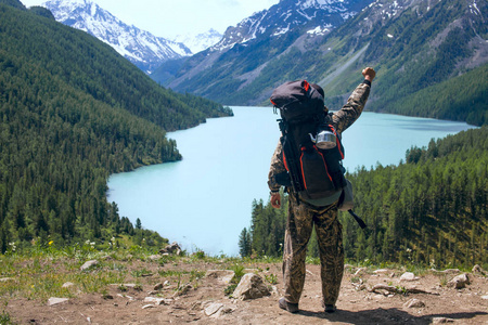 一个举起手的人看着一个山湖的喜悦。