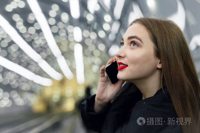 漂亮的女孩走进地铁站看着她的手机图像