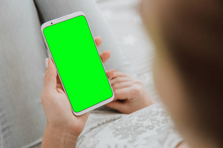 模拟色度关键图像的妇女的手绿色屏幕智能手机。拿着手机。特写