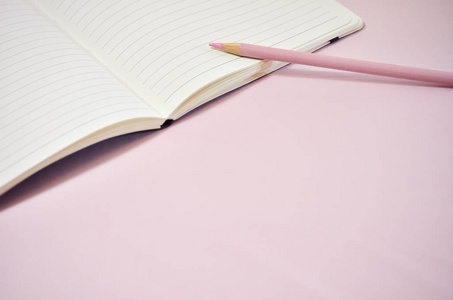带铅笔的粉红色背景空白笔记本