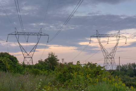 双子电力线塔在一个大的开放的领域在阴天日落。