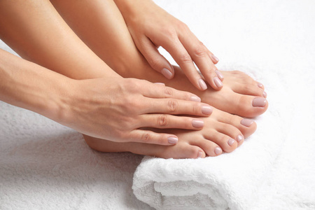 女人用白色毛巾特写触摸她光滑的脚。 水疗护理