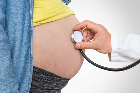 儿科医生用听诊器听孕妇的心跳婴儿怀孕概念