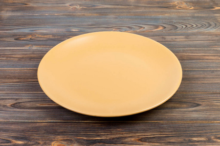 透视图。 空黄色哑光盘晚餐在深色木制背景。