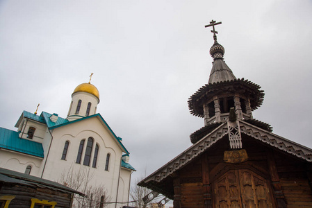 圣彼得堡俄罗斯木制小教堂与钟楼和雕刻门廊在圣圣萨拉菲姆维利茨基教堂。 美丽的寺庙，顶着天空有一个金色的穹顶。