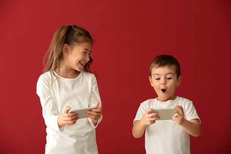 可爱的小孩子在彩色背景上玩智能手机
