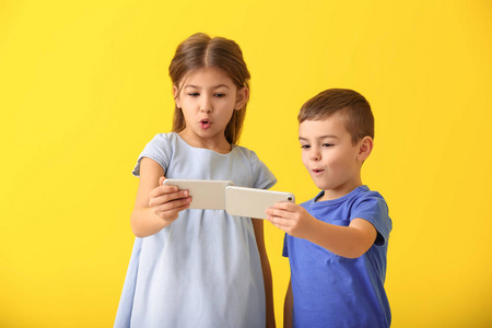 可爱的小孩子在彩色背景上玩智能手机