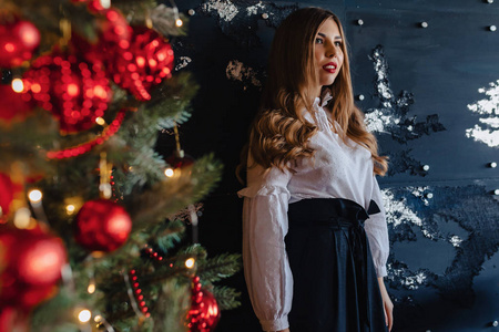 一个年轻迷人的女孩穿着节日的服装，背景是圣诞树，主题是新年