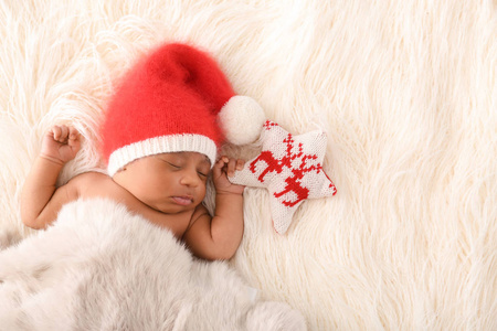可爱的非洲裔美国婴儿戴着圣诞老人帽子睡在白色毛茸茸的格子呢上