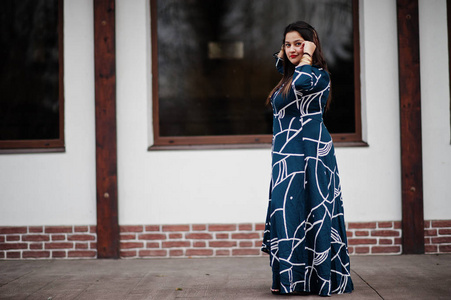 深色印度女人穿着长而时尚的裙子在户外摆姿势。