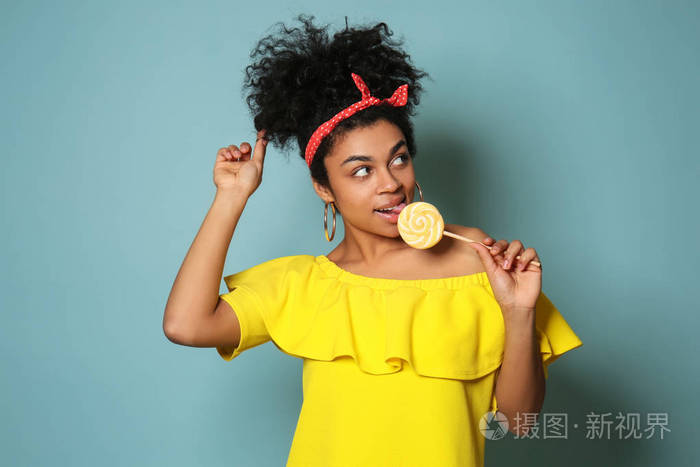 美国黑人年轻女子带棒棒糖的彩色背景肖像