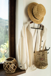 柳条帽和袋子挂在家里走廊的白色墙上
