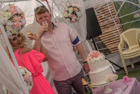 新婚夫妇在白色蛋糕旁边喝友谊香槟杯。 在澳大利亚惊人的沙滩上参加婚礼。