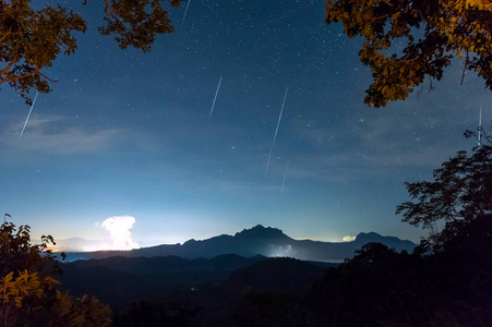 双子座流星雨在夜空中与薄雾在山上长时间暴露，梅莫兰芒泰国。