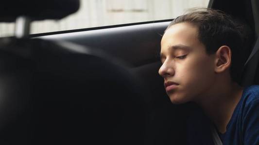 关闭。睡在汽车后座上的十几岁男孩