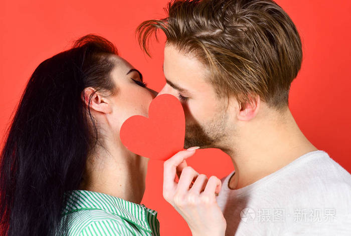 情侣在爱亲吻和隐藏的嘴唇背后的心卡可爱夫妇的感性吻近在咫尺男人和