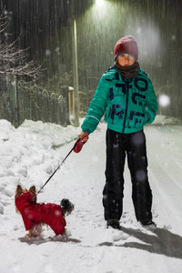 男孩在冬天和狗一起散步，在大雪的夜晚