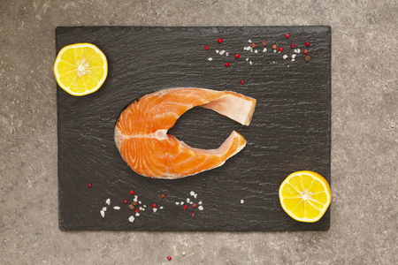 新鲜鲑鱼牛排，加香料和柠檬，放在黑色石板板上