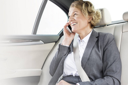 微笑的女商人在旅途中在车上谈论智能手机
