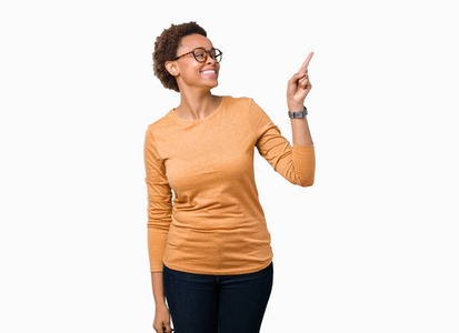 年轻漂亮的非洲裔美国妇女戴着眼镜，戴着孤立的背景，脸上带着大大的微笑，用手和手指指向一边，看着相机。