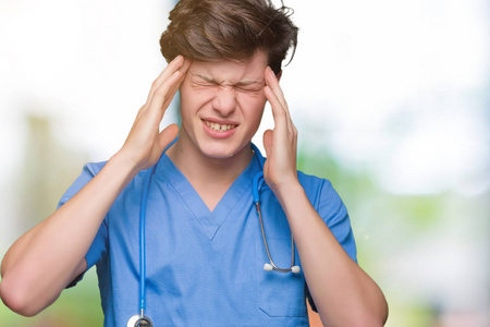 年轻的医生穿着医疗制服，在孤立的背景下患有头痛，绝望和压力，因为疼痛和偏头痛。 手放在头上。