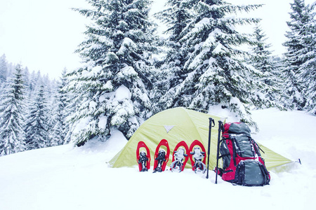 帐篷冬天的山。帐篷矗立在雪地里的山上。 雪鞋在帐篷旁边。