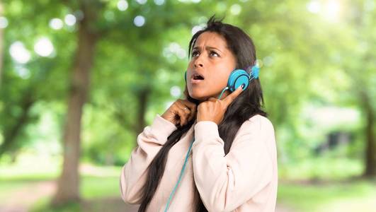 美国年轻女子在户外用耳机听音乐