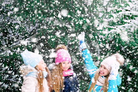 幸福的金发小女孩在雪杉树的背景下。